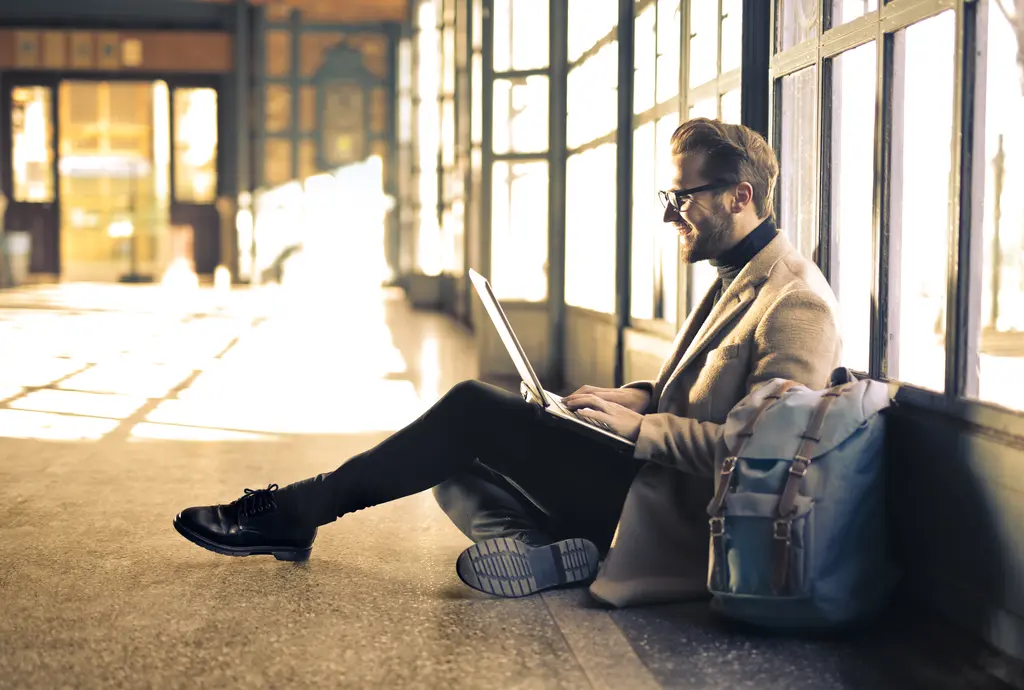Person sitting by a window using a laptop
